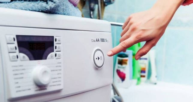 Женщина включает стиральную машинку